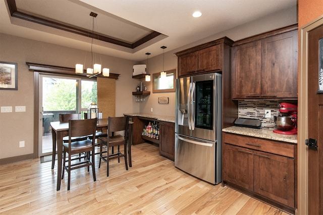 kitchen with decorative light fixtures, light wood-type flooring, a chandelier, and stainless steel refrigerator with ice dispenser