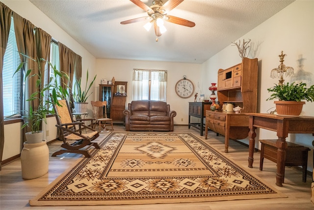 living room featuring a textured ceiling, wood-type flooring, and ceiling fan