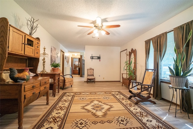 sitting room with a textured ceiling, ceiling fan, and light wood-type flooring