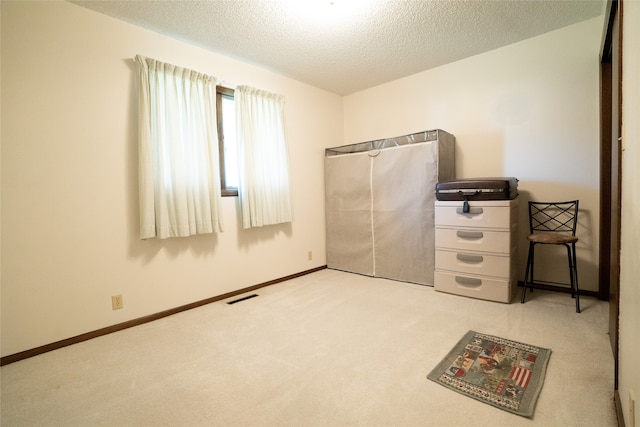 unfurnished bedroom with a textured ceiling and light colored carpet