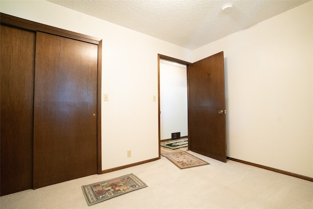 bedroom with a closet, light carpet, and a textured ceiling