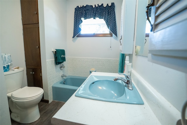 bathroom with toilet, a tub to relax in, sink, tile walls, and hardwood / wood-style flooring