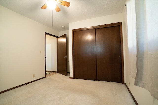 unfurnished bedroom with a textured ceiling, light colored carpet, ceiling fan, and a closet