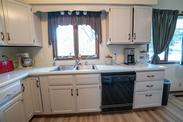 kitchen with black dishwasher, white cabinetry, light hardwood / wood-style flooring, and sink