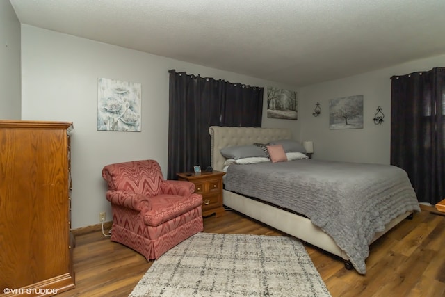 bedroom with a textured ceiling and wood-type flooring