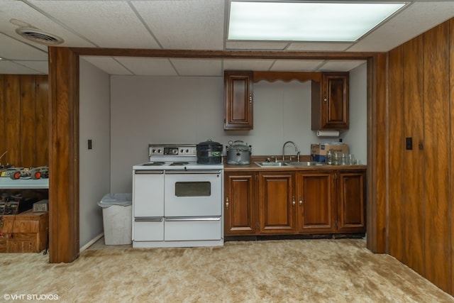 kitchen with wood walls, white range with electric stovetop, sink, and light carpet