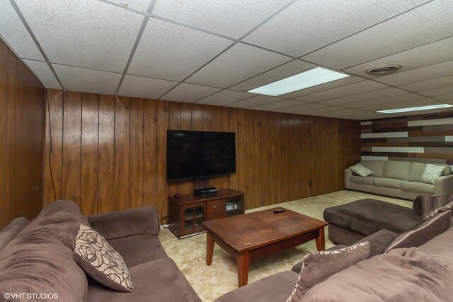 living room featuring wood walls and a paneled ceiling