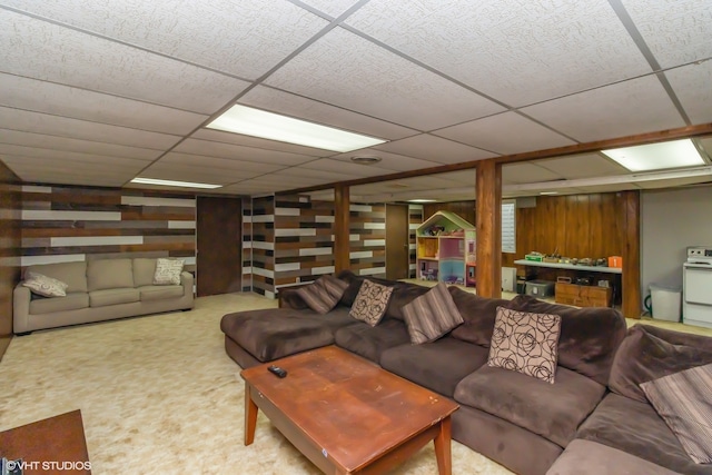 living room with a paneled ceiling, wooden walls, and carpet floors