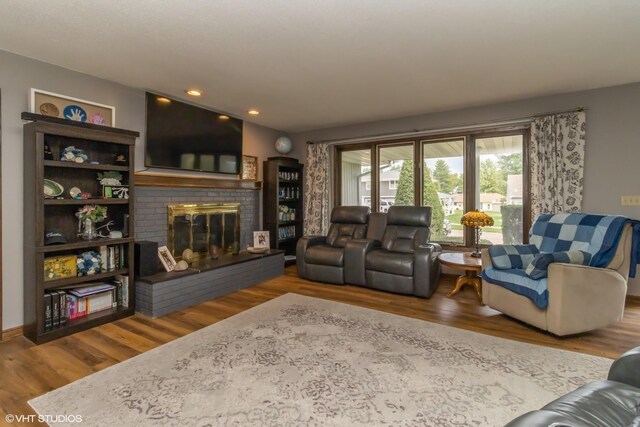 living room with wood-type flooring and a brick fireplace