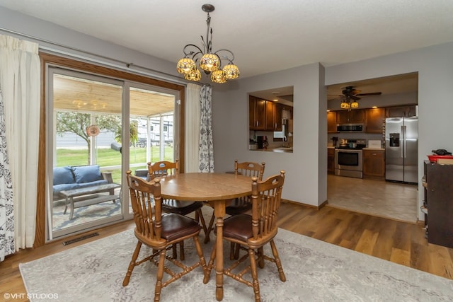 dining room with ceiling fan with notable chandelier and hardwood / wood-style flooring