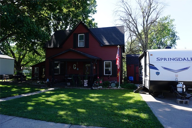 view of front facade with a front lawn, covered porch, and roof with shingles