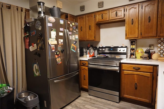 kitchen featuring brown cabinetry, appliances with stainless steel finishes, light countertops, and light wood-style floors