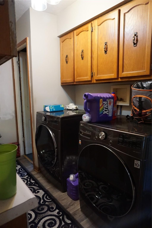 laundry area with cabinet space, separate washer and dryer, and wood finished floors