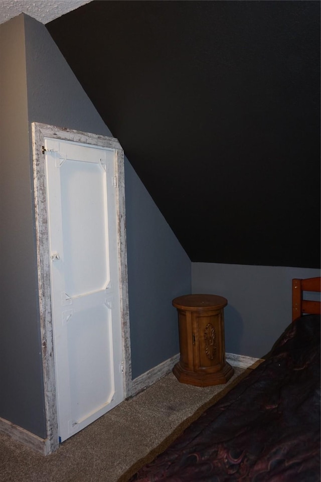 unfurnished bedroom featuring vaulted ceiling, baseboards, and carpet floors