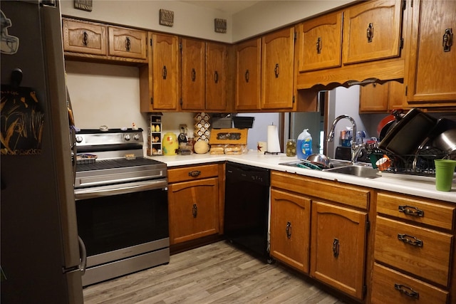 kitchen featuring stainless steel electric stove, dishwasher, brown cabinets, freestanding refrigerator, and a sink