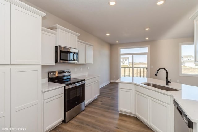 kitchen with stainless steel appliances, dark hardwood / wood-style flooring, white cabinets, and sink