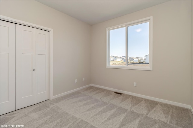 unfurnished bedroom with light carpet and a closet