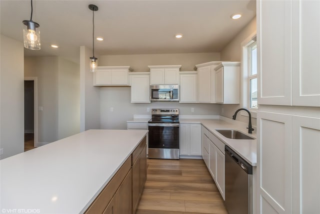 kitchen featuring appliances with stainless steel finishes, pendant lighting, white cabinets, and sink