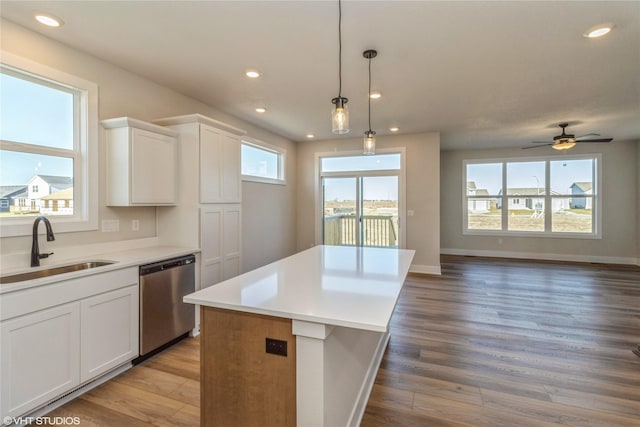 kitchen featuring white cabinets, a center island, decorative light fixtures, sink, and stainless steel dishwasher