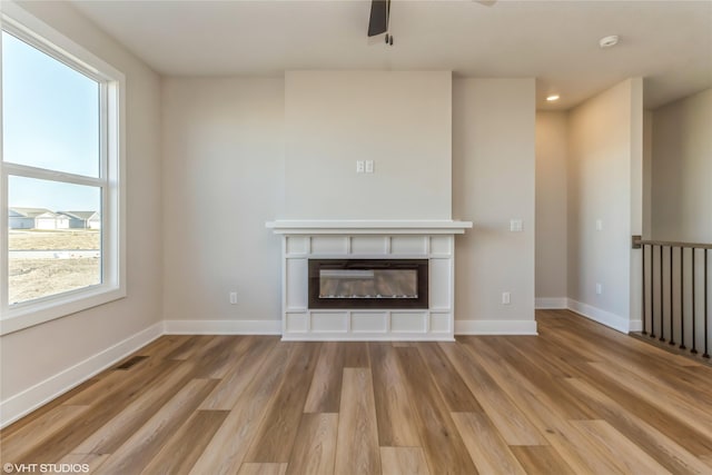 unfurnished living room featuring ceiling fan, plenty of natural light, and light hardwood / wood-style floors