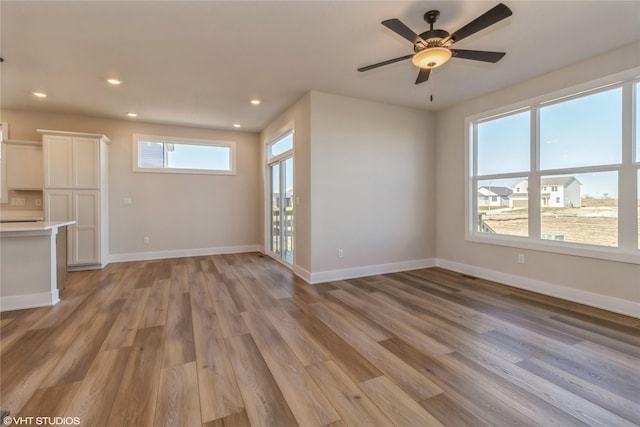 unfurnished living room featuring ceiling fan, plenty of natural light, and light hardwood / wood-style flooring