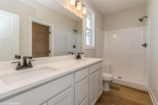 bathroom featuring walk in shower, vanity, wood-type flooring, and toilet