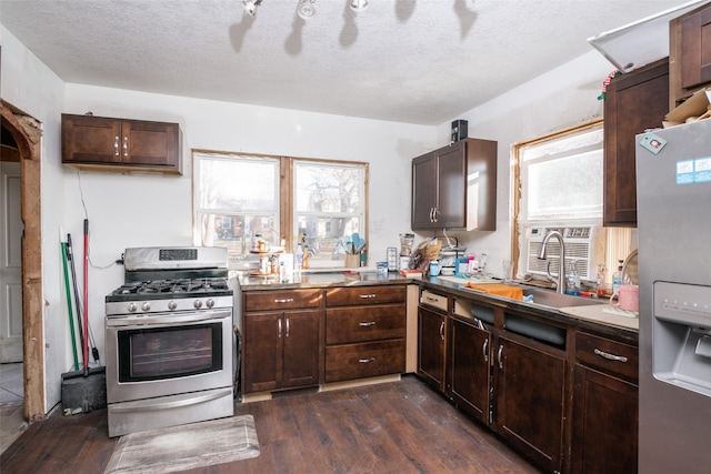 kitchen with a textured ceiling, dark brown cabinets, dark wood-type flooring, and appliances with stainless steel finishes