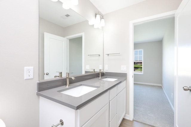 bathroom featuring double vanity, a sink, visible vents, and baseboards