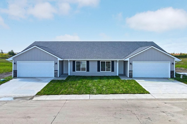 single story home featuring stone siding, a front yard, concrete driveway, and an attached garage