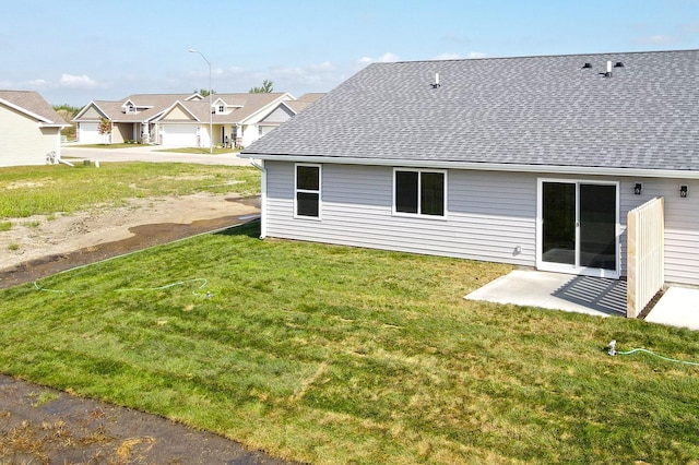 back of house featuring a residential view, roof with shingles, and a yard