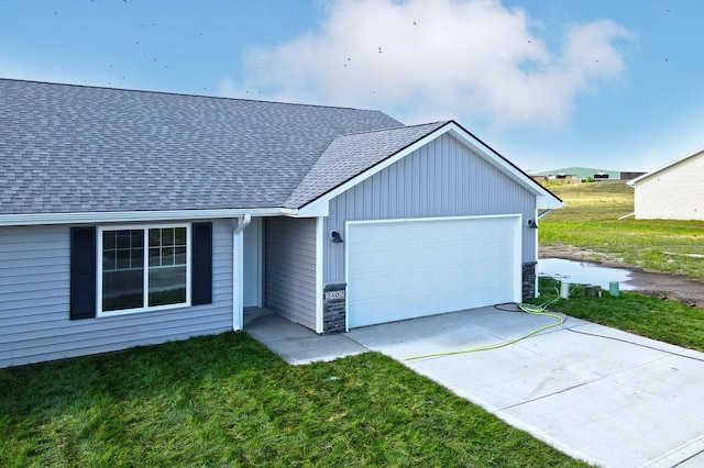 ranch-style home featuring concrete driveway, stone siding, roof with shingles, an attached garage, and a front yard