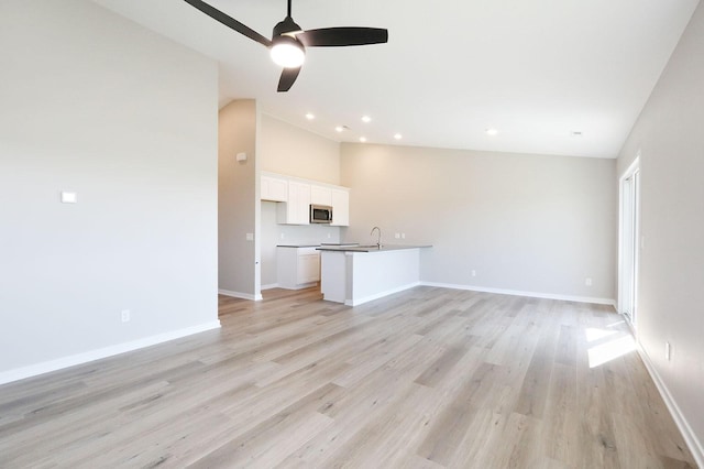 unfurnished living room with light wood-style floors, lofted ceiling, baseboards, and recessed lighting