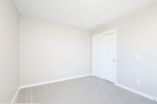 unfurnished bedroom featuring carpet floors, a closet, and baseboards