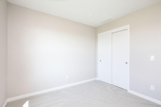 unfurnished bedroom featuring carpet, baseboards, and a closet