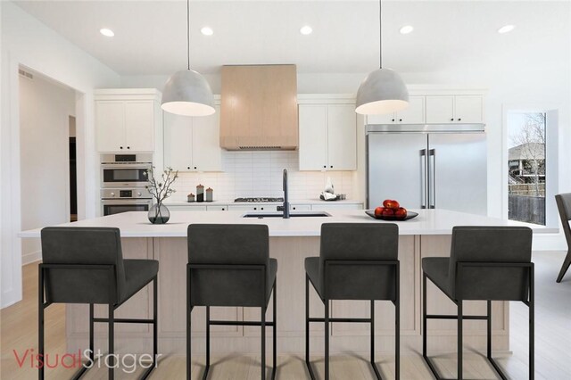 kitchen featuring an island with sink, stainless steel appliances, sink, and white cabinetry