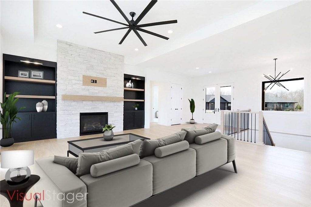 living room with a fireplace, light hardwood / wood-style floors, a chandelier, and built in shelves