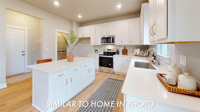 kitchen featuring white cabinets, a center island, light wood-type flooring, and appliances with stainless steel finishes