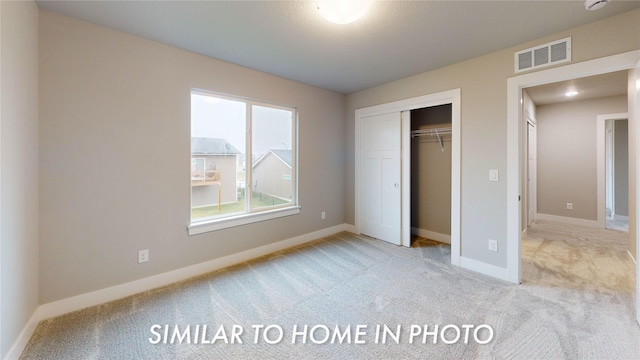 unfurnished bedroom with light carpet and a closet