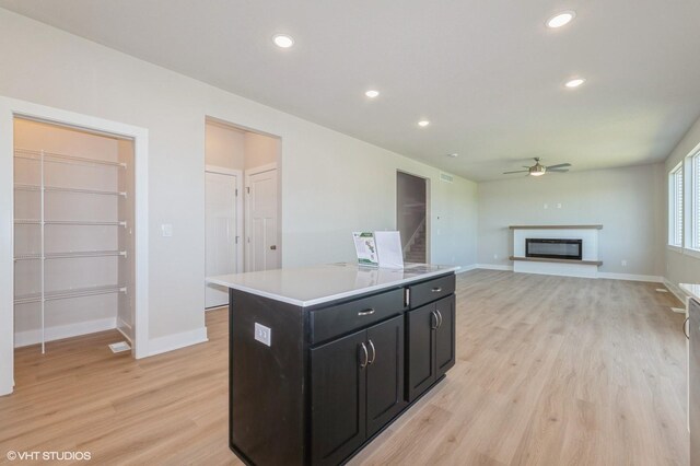 2231 Chan Dr, Adel, IA 50003 - kitchen with dark cabinetry, ceiling fan, light wood-style floors, recessed lighting, and a kitchen island