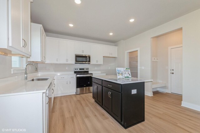 2231 Chan Dr, Adel, IA 50003 - kitchen featuring stainless steel appliances, dark cabinets, light wood finished floors, white cabinets, and recessed lighting