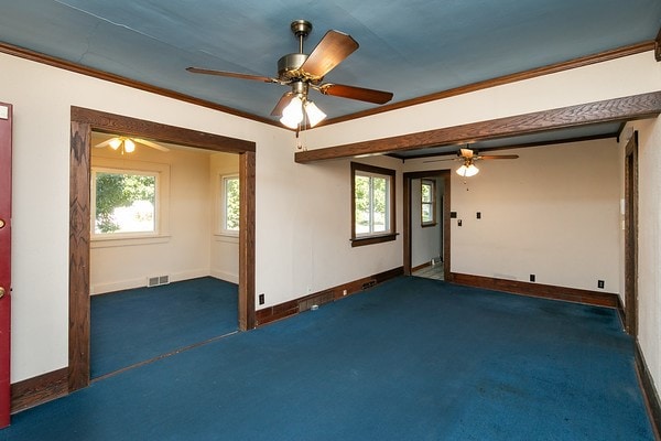 unfurnished room with crown molding, carpet flooring, and ceiling fan