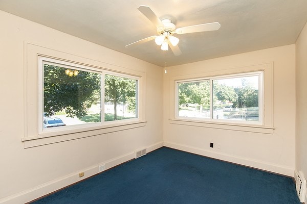 empty room with ceiling fan, plenty of natural light, carpet, and a baseboard radiator