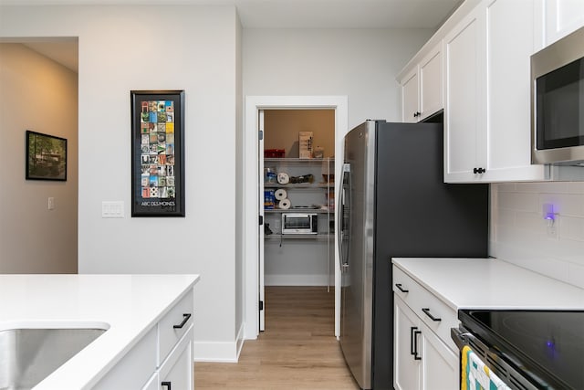 kitchen featuring light wood-type flooring, white cabinets, and tasteful backsplash