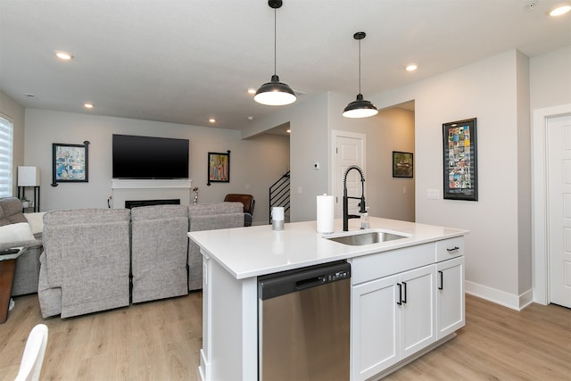 kitchen with decorative light fixtures, an island with sink, sink, stainless steel dishwasher, and white cabinets