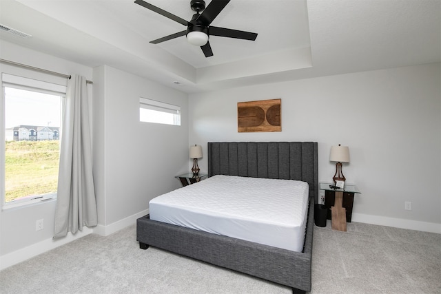 bedroom featuring light colored carpet, ceiling fan, and a tray ceiling