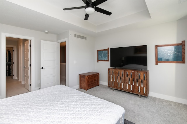 bedroom featuring light colored carpet, ceiling fan, and a raised ceiling