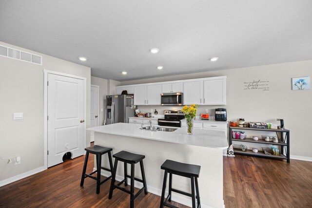 kitchen with visible vents, a breakfast bar, stainless steel appliances, light countertops, and white cabinets