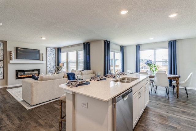 kitchen featuring dishwasher, a textured ceiling, white cabinets, and a center island with sink