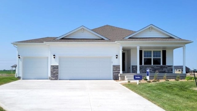 view of front of house featuring a garage, stone siding, driveway, and a porch