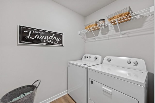 washroom with washer and dryer, laundry area, baseboards, and light wood finished floors